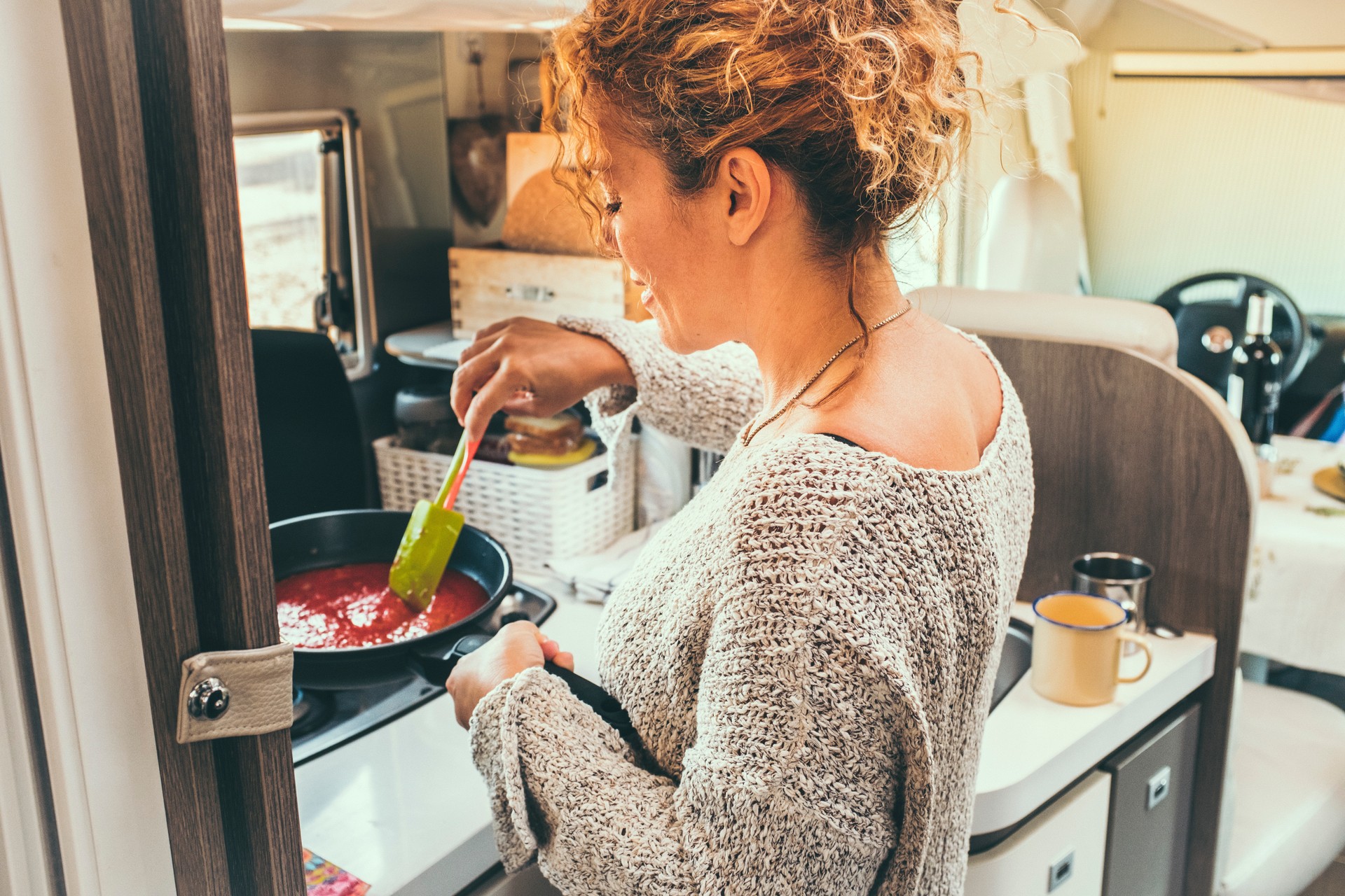 Side View Of Woman Cooking In Camper Van